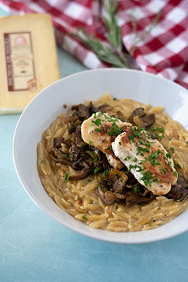 Bowl of pasta topped with mushrooms and chicken breasts