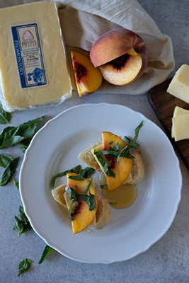 two slices of baguette stacked with peaches, basil, and a honey drizzle