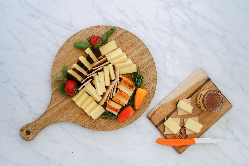 A circular board with cut cheeses garnished with greenery.
